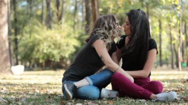 Gay couple girlfriends kissing and hanging out together at the park