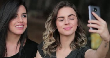 Friends together outside holding cellphone taking selfie