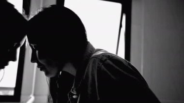 Depressed woman leaning on bathroom mirror reflection feeling sad and in distress. Monochromatic