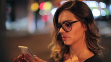 Woman typing on cellphone at night