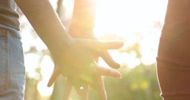 Hands held together with sunlight flare in the background
