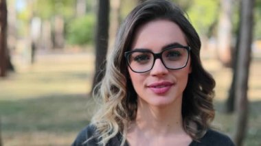 Blonde girl wearing glasses looking to camera, intelligent smart woman smiling to camera