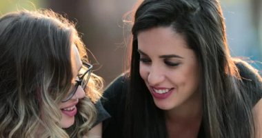 Friends gossiping talking to each other in conversation outside in the sunlight