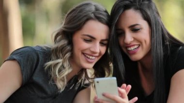 Candid Girlfriends looking at their cellphone outdoors on social media