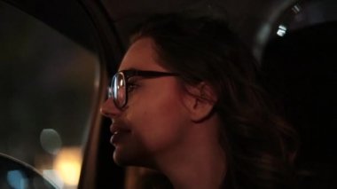 Woman looking out car window at night. Woman starring at city lights