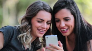 Girlfriends looking at their cellphones on social media laughing