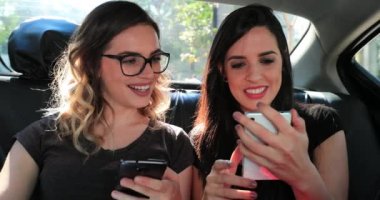 Girls looking at cellphone in the back seat of a car