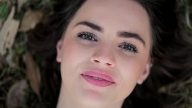 Attractive girl asleep laying on grass at park opening eyes smiling and alughing to camera