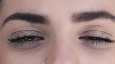 Pretty eyes looking to camera smiling. Macro of green eyes opening and closing