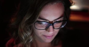 Girl typing on her cellphone in the back seat of a car at night
