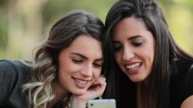 Candid Girlfriends looking at their cellphone outdoors on social media