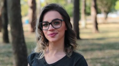 Blonde girl wearing glasses looking to camera, intelligent smart woman smiling to camera