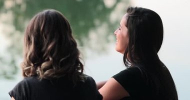 Candid close-up of young woman speaking to friends laughing and smiling. Girl in conversation outdoors