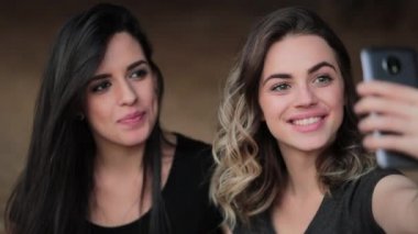 Friends posing together for selfie holding cellphone