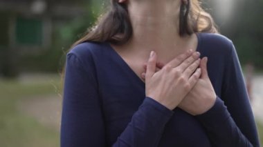 Grateful woman with hands in chest standing outdoors in nature. Hopeful person hand in heart