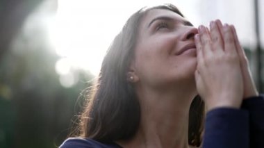 Hopeful person looking at sky smiling. Faithful religious woman in prayer feeling the presence of GOD