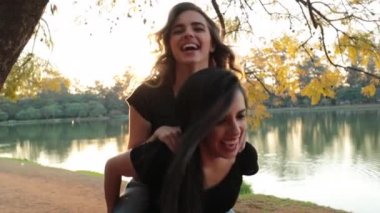 Girl piggy backing on friend and/or lover back during sunset golden hour. LGBT couple in romantic piggy back scene