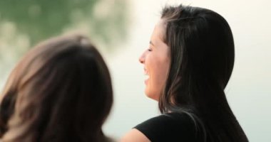 Candid close-up of young woman speaking to friends laughing and smiling. Girl in conversation outdoors
