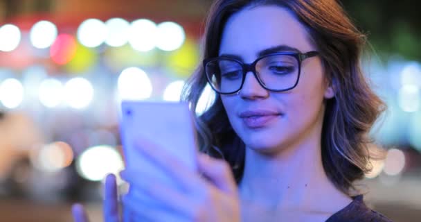 Девушка Очках Проверяет Мобильный Телефон Ночью Городской Атмосфере — стоковое видео