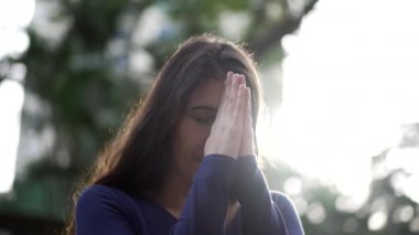 Woman praying outside looking up at sky with HOPE and FAITH. Spiritual person in prayer feeling the presence of GOD