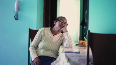 A thoughtful senior black woman sitting at home thinking by herself