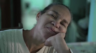 A contemplative senior black woman face. One pensive hispanic older lady in 70s