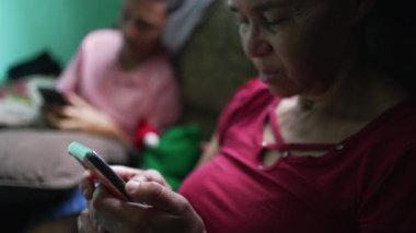Üst düzey İspanyol kadın evde akıllı telefon cihazına bakıyor.