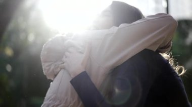 Two young women embrace outside. Joyful friends hugging each other in friendship. Togetherness concept