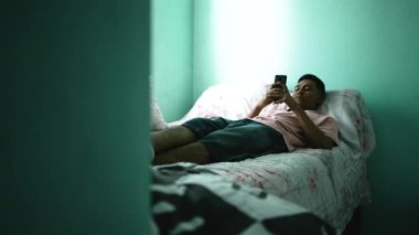 Revealing one young hispanic man in bedroom checking smartphone device online