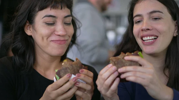 Two Happy Female Friends Eating Burgers Same Time Young Women — Φωτογραφία Αρχείου