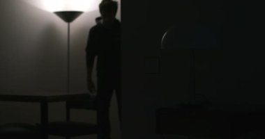 Genç adam eve geliyor, ışıkları açıyor.