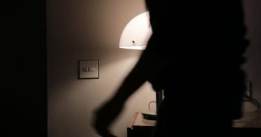 Person leaving apartment turning off lamp