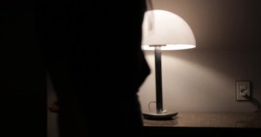 Person arriving home turning on lamp