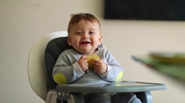 Adorable cute baby smiling to camera on highchair