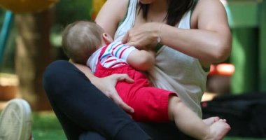 Mother breastfeeding baby boy outside casual and candid