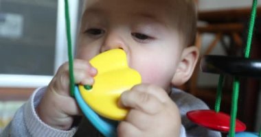 Toddler baby putting toy in mouth teething and discovering the world