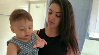 Mom teaching how to brush teeth to playful infant boy