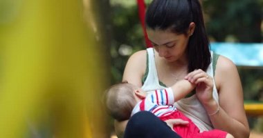 Candid mother holding baby infant boy outside at park