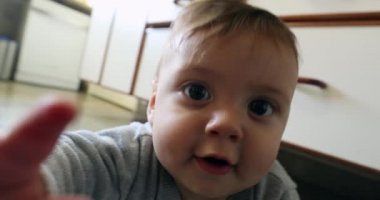 Baby infant at kitchen floor wanting to touch camera playing