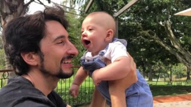 Casual authentic interaction with baby infant and father at park outdoors