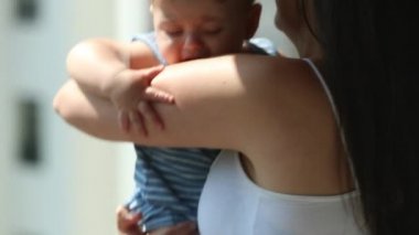 Candid mother holding baby infant son in balcony