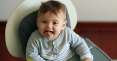 Happy baby with mouth full eating meal