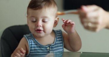 Feeding baby infant boy mother trying to feed meal to toddler son