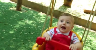 Baby boy at park swing having fun smiling laughing