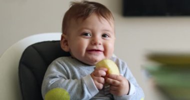 Authentic baby smile happy holding piece of apple