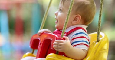 Adorable cute baby infant boy child at playground park swing