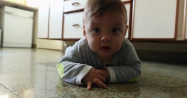 Happy baby boy on kitchen floor smiling to camera
