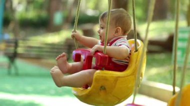 Beautiful baby boy at playground park swing in slow-motion