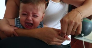 Mom cutting trimming baby son nails upset infant crying