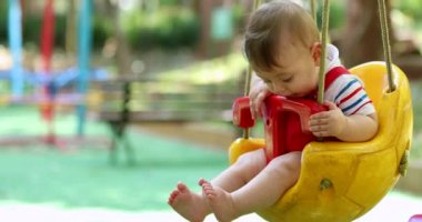Joyful baby boy toddler at playground swing at park